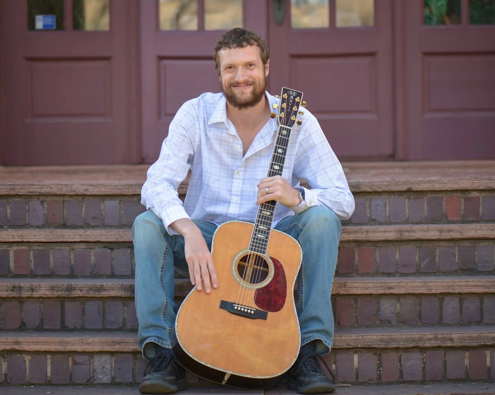 John Will seated with his acoustic guitar